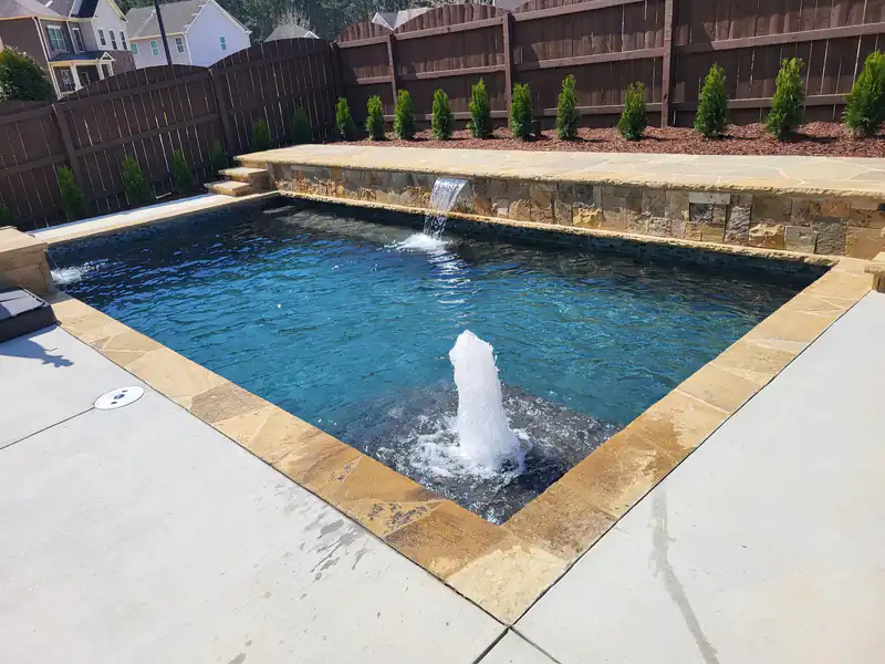 Rectangular pool with a stone sheer-descent wall, a bubbler and flagstone coping