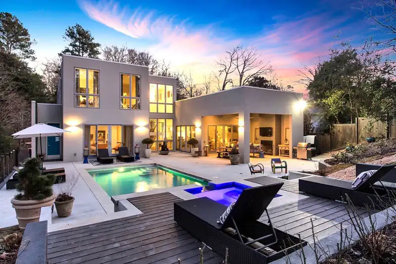Modern home at dusk with a lit swimming pool and spa in the yard