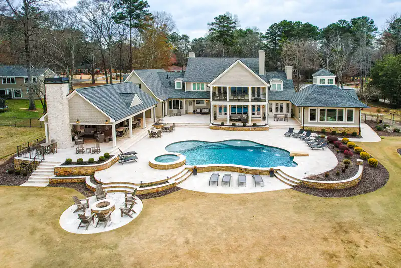 Aerial view of an estate pool and spa wrapped in stone terraces and a fire pit