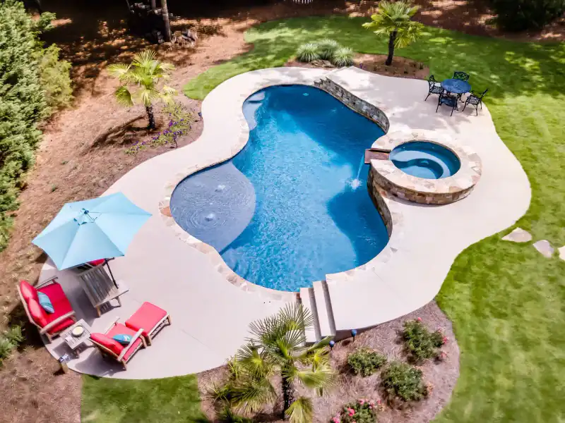 Aerial view of a freeform pool and spa with umbrellas and palms