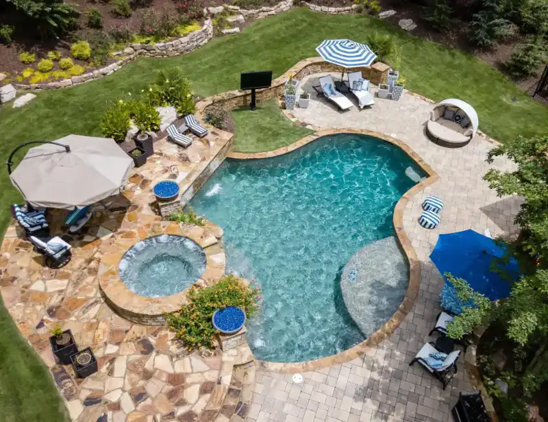 Aerial view of a freeform pool and spa with a fire pit and a daybed