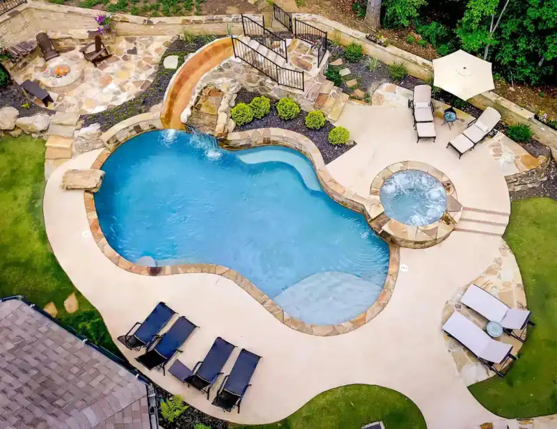 Aerial view of a freeform pool with a slide and boulders